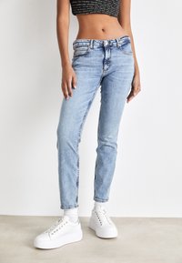 Ljusblå denimjeans med smal passform, med knäppning framtill, fem fickor och kontrastsömmar. Matchas med vita plattformssneakers.