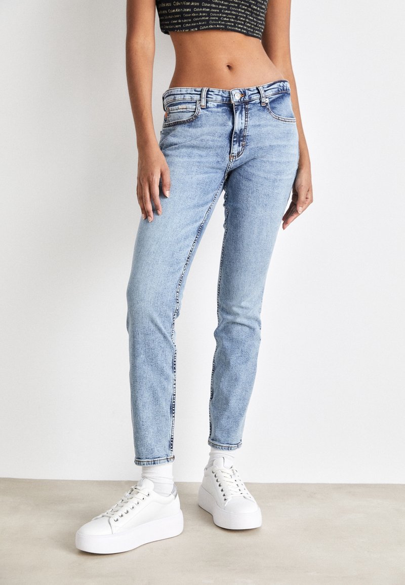 Ljusblå denimjeans med smal passform, med knäppning framtill, fem fickor och kontrastsömmar. Matchas med vita plattformssneakers.