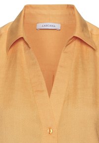 Yellow collared blouse with a placket, featuring a small button and a smooth, slightly shiny texture. Label reads "Lascana."