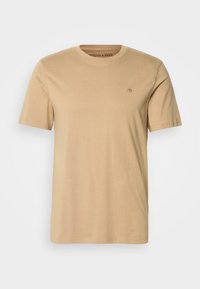 Camiseta de algodón beige con cuello redondo, mangas cortas y un pequeño logo bordado en el pecho. Textura suave y corte estándar.