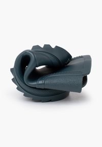 Sandale en caoutchouc bleu foncé, avec une surface texturée, des sangles flexibles et une semelle épaisse et crantée. Le design enroulé met en valeur son matériau doux.