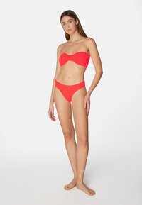 Röd bikinitopp med bandeau-design och knutdetalj samt högskurna bottnar. Tillverkad av textil med en livfull, enfärgad nyans.
