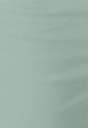Lichtgroene stof met een fijne geribbelde textuur en subtiele diagonale lijnen, met zachte plooien en kreukels.
