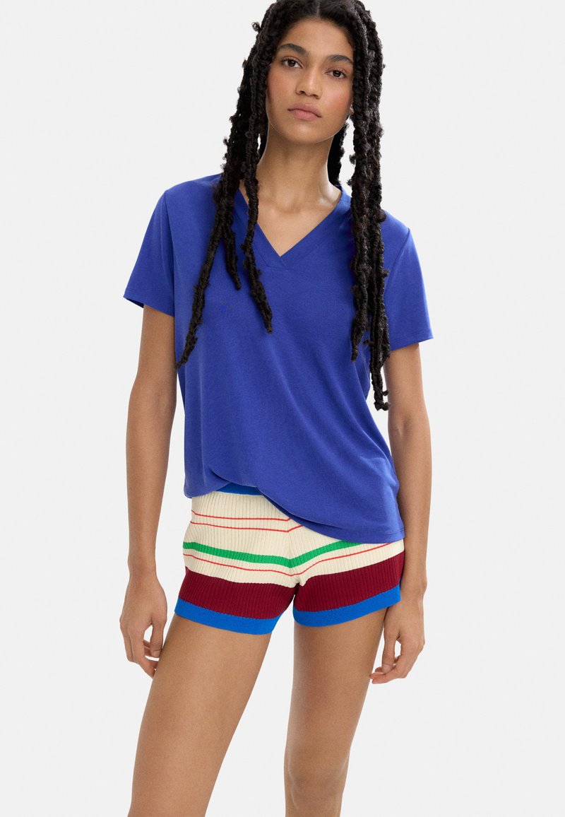 Niebieska koszulka z dekoltem w serek wykonana z miękkiego materiału, połączona z wielokolorowymi krótkimi spodenkami z prążkowanego materiału w czerwone, zielone i kremowe paski z niebieskimi akcentami.