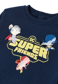 Felpa blu navy con colletto a coste, caratterizzata da personaggi dei cartoni animati colorati Superman, Batman e Flash sopra il testo "DC SUPER FRIENDS."