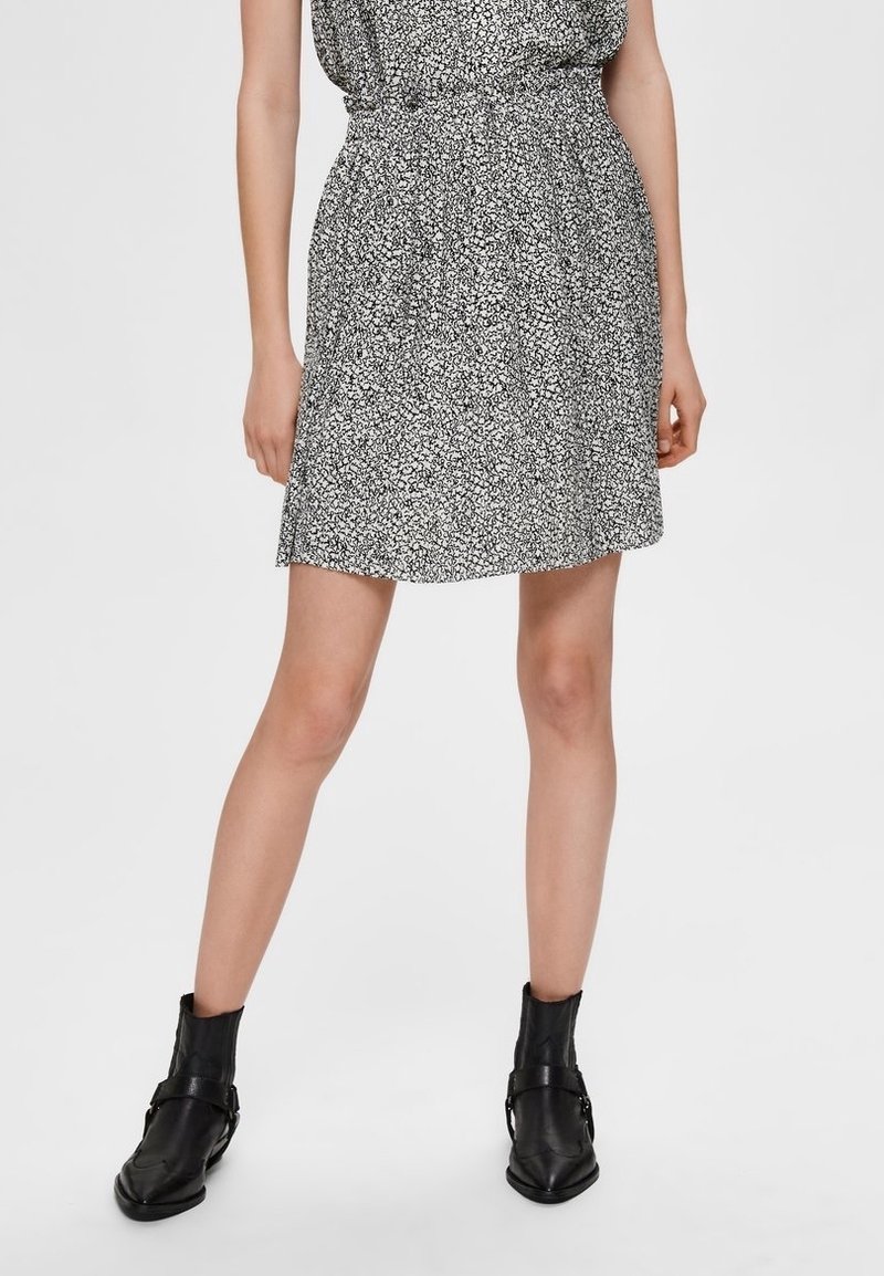 Robe courte noir et blanc avec imprimé floral, taille cintrée et silhouette fluide. Associée à des bottines noires.