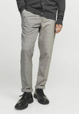 Pantalones de cuadros grises con un patrón a cuadros, que presentan un corte entallado y puños enrollados, combinados con zapatos negros de cordones.