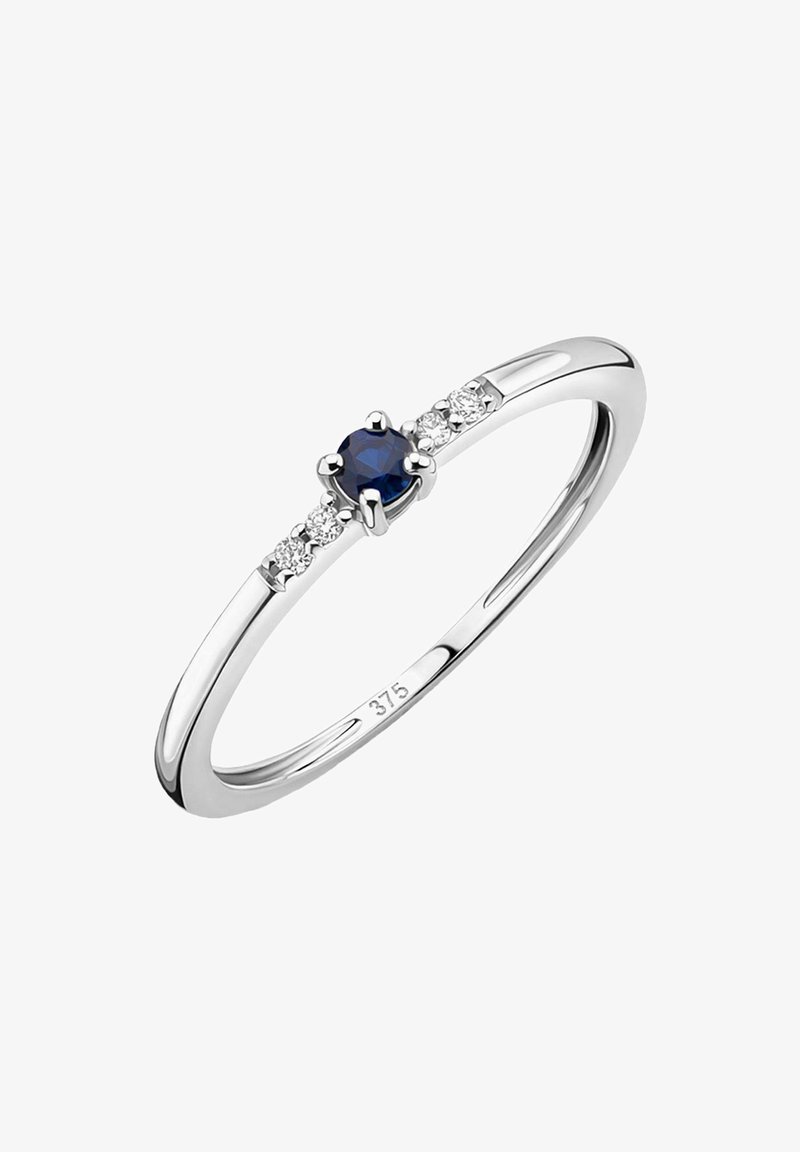 Silverring med en central rund blå safir, flankeras av fyra små klara stenar, med en polerad slät finish och en något avsmalnande band.