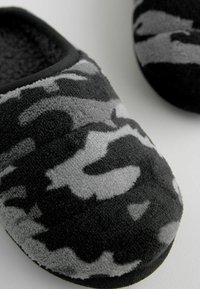 Chaussons en camouflage noir et gris avec une tige en tissu doux, un bout arrondi et une doublure intérieure en peluche pour plus de chaleur et de confort.