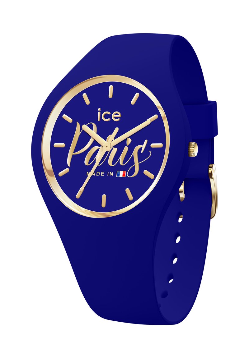 Reloj de silicona azul con esfera redonda, marcadores y manecillas de color dorado, y texto en cursiva "París". Presenta una correa con hebilla.