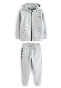 Sudadera gris con cremallera y bolsillos frontales, combinada con pantalones de chándal a juego que cuentan con una cinturilla elástica y una costura lateral decorativa.