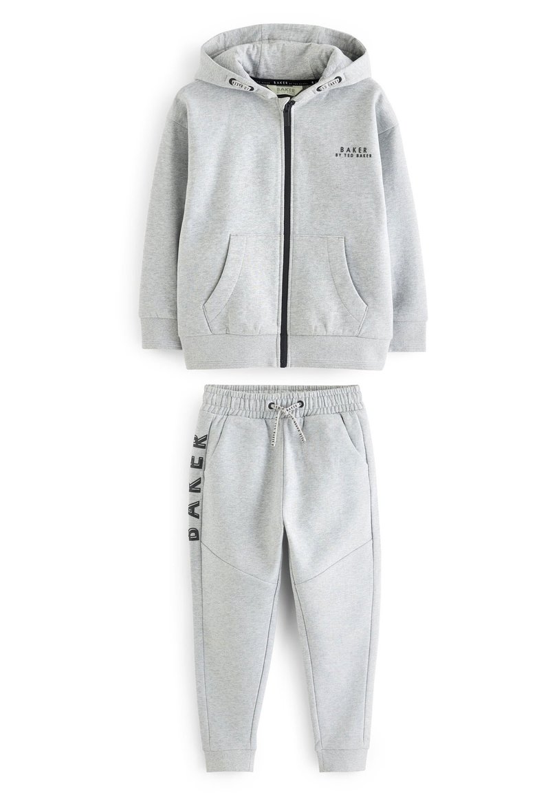 Sudadera gris con cremallera y bolsillos frontales, combinada con pantalones de chándal a juego que cuentan con una cinturilla elástica y una costura lateral decorativa.