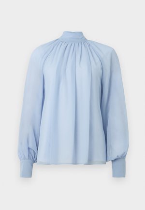 Blouse longue à manches longues bleu clair avec un col montant, tissu froncé au niveau du col et poignets ajustés sur un fond blanc uni.