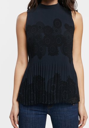 Top negro sin mangas plisado con cuello alto y sutiles patrones de encaje floral, combinado con vaqueros azules.