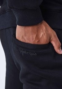 Zwarte sweatshirt met geribbelde manchetten, voorzien van een zijzak. Geborduurd 'Project Paris' logo in bijpassend zwart op de zak.