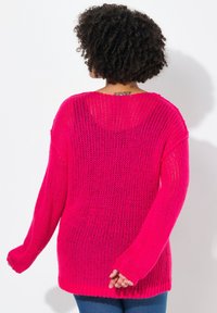 Jasnoróżowy, oversize'owy sweter z dzianiny o luźnym, otwartym splotcie, opadających ramionach i długich rękawach. Żebrowany dół i mankiety.