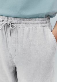 Light gray linen shorts with an elastic waistband, adjustable drawstring, and side pockets, showcasing a soft, textured fabric.