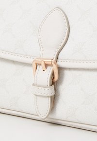 Borsa di un colore off-white con una patta in pelle liscia e una chiusura in metallo rosa dorato. Presenta un motivo sottile su tutta la superficie.