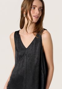 Schwarzes ärmelloses Oberteil mit V-Ausschnitt und strukturiertem Stoff. Es hat einen lockeren Schnitt und subtile Nahtdetails, die ein minimalistisches Design ergänzen.