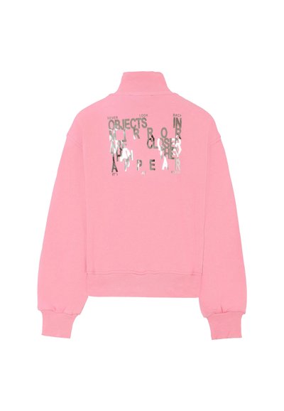 Roze cropped sweatshirt met hoge kraag, voorzien van reflecterende tekst in zwart en zilver, geplaatst op de achterkant tegen een gestructureerde stof.
