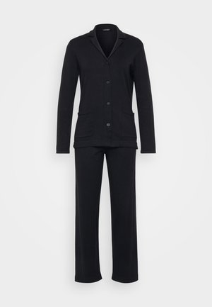 Μαύρο σέτ lounge που περιλαμβάνει ένα πουκάμισο με γιακά σε σχήμα V και δύο μπροστινές τσέπες, σε συνδυασμό με αντίστοιχα μακριά παντελόνια σε πιο χαλαρή γραμμή.