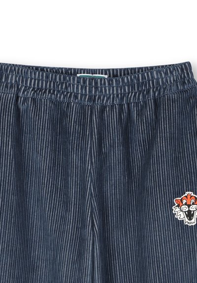Pantalon en velours côtelé bleu marine avec une taille élastique et un petit visage de tigre cartoon orange et blanc sur la jambe droite.