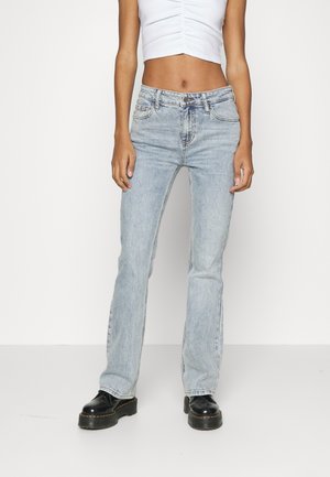 Lyseblå denimflared jeans med mid-rise liv, med et klassisk fem-lommen design og sømdetaljer, kombinert med svarte platåstøvler.