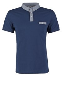 Marinblå polo med en chambray-krage, tvåknappsknäppning och en liten bröstficka. Tillverkad av en mjuk bomullsblandning.
