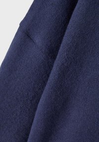 Tessuto di un blu navy con una finitura morbida, caratterizzato da una superficie leggermente rialzata e pelosa e una caduta fluida. Vista ravvicinata del materiale.