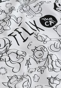 Gatti da cartone animato in bianco e nero con varie espressioni circondano la parola "TILLY" e un cerchio etichettato "The CA" su tessuto.