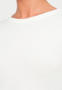 Λευκό μπλουζάκι με ριμπ ύφανση, διαθέτει στρογγυλή λαιμόκοψη και απαλό υφή, με ελαφριά ελαστικότητα και λεία επιφάνεια.