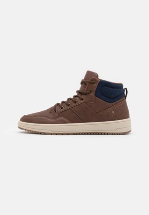 Baskets montantes marron avec col rembourré bleu marine, semelle beige et lacets sur le devant sur fond blanc.
