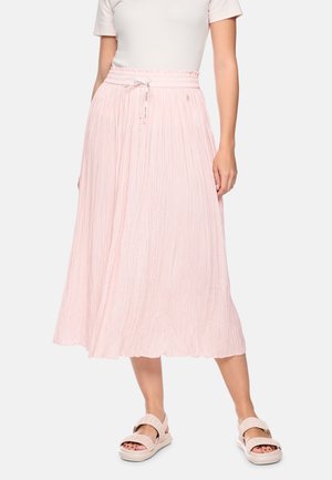 Woman wearing a light pink pleated midi skirt with a drawstring waist, white top, and matching pink sandals on a white background.