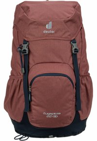 Mochila de tela roja con solapa superior, bolsillo frontal con cremallera, bolsillos de malla en los laterales, correas ajustables y panel inferior azul oscuro. Presenta logo.