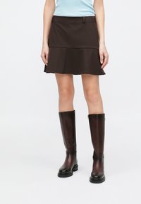 Brown flared skirt with a layered design, paired with knee-high, dark brown leather boots featuring a chunky sole and zipper detail.
