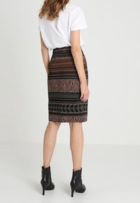 Polvista pitkä, tiukasti istuva hame, jossa on monivärinen kuviointi, jossa on raitoja ja eläinkuosia, valmistettu teksturoitusta kankaasta, yhdistettynä nilkkureihin.