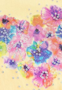 Blumenstoff mit bunten Blumen in Pink, Blau und Gelb, verziert mit verstreuten silbernen Pailletten auf einem hellgelben Hintergrund.