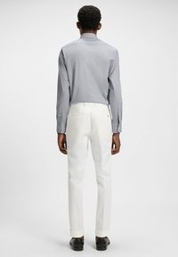 Ljust blå randig skjorta med knappar och långa ärmar, kombinerad med vita skräddarsydda byxor och svarta skor. Enkel, klassisk design.