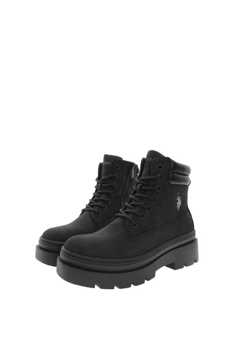 Stivaletti neri in suede alla caviglia con una suola in gomma spessa, dotati di lacci frontali, cerniera laterale e dettaglio del logo sul lato esterno.