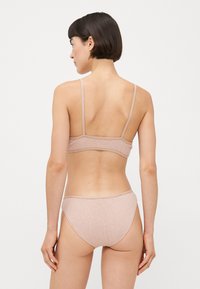 Light pink cotton bra with thin straps and matching bikini bottoms. Smooth texture and simple design without additional patterns or hardware.