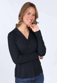 Black long-sleeve button-up blouse with a collar, featuring a smooth texture and front buttons, worn with blue jeans.