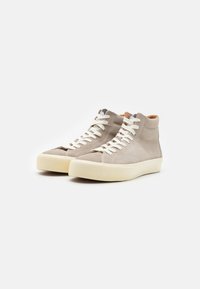 Høye sneakers i lysegrå semsket skinn, med hvite snørebånd, rund tå og kremfarget gummisåle. Subtile sømdetaljer er synlige.