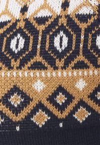 Stickad tröjmönster med geometriska mönster i marinblått, guld och vitt. Texturerad tyg med distinkta diamantformer och detaljer.