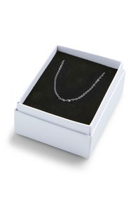 Collier en chaîne argentée présenté dans une boîte blanche avec un intérieur en velours noir. Le collier comporte de fines mailles disposées dans un design délicat.