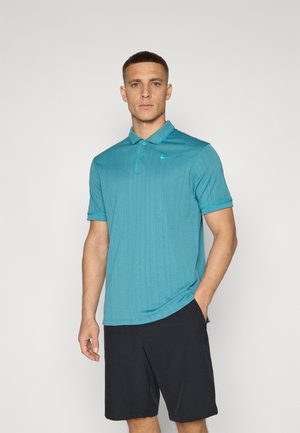 Polo en teal avec un motif de rayures verticales subtil, à manches courtes et col pointu. Logo Nike en accent bleu clair. Shorts noirs.