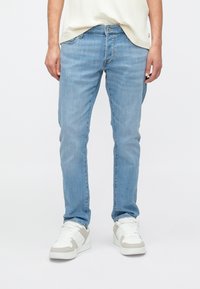 Hele sinised denimist teksad, õhuke lõige, viis taskut ning kerge pleekimine. Kandmisega valgete tossudega, millel on hallid detailid.