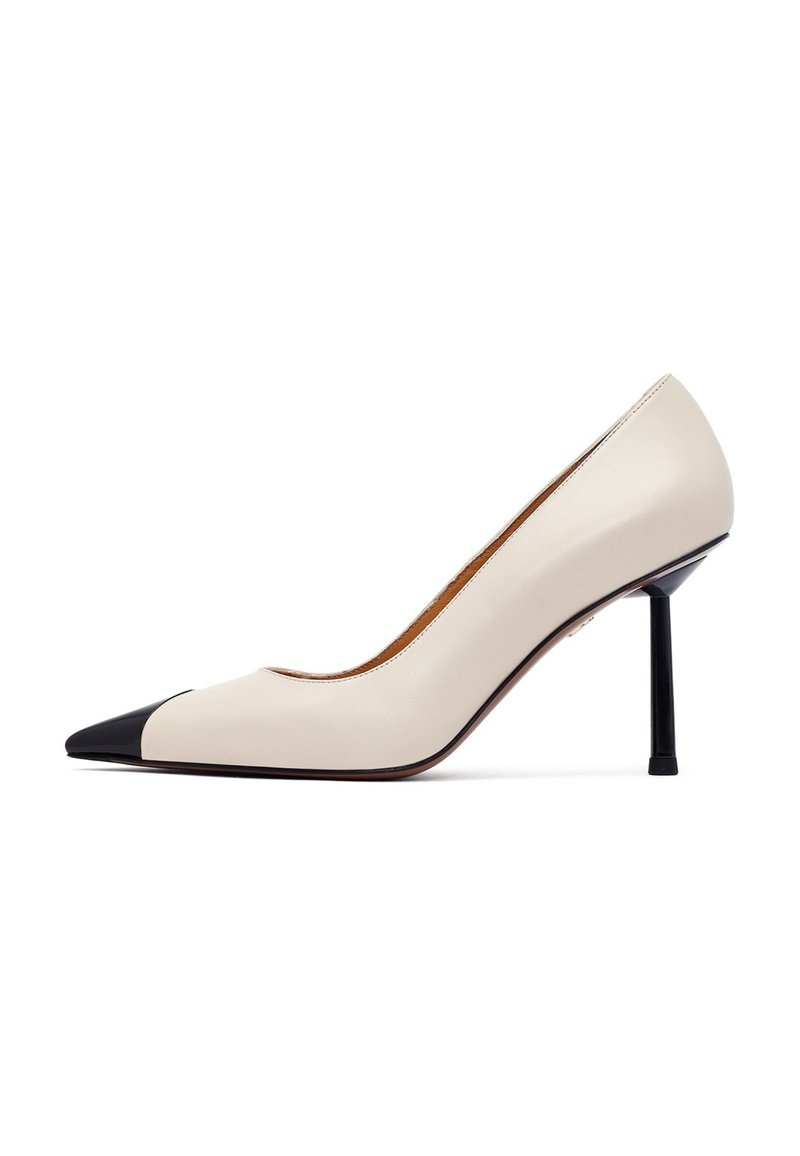 Beżowe skórzane czółenka z wąskim noskiem, czarnym noskiem oraz smukłym czarnym obcasem typu stiletto. Gładka faktura i minimalistyczny design.