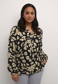 Blouse noire avec un décolleté en V et des manches longues, ornée d'un imprimé floral crème. Texture lisse ; coupe décontractée.