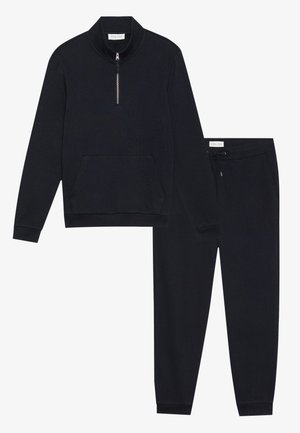 Zwarte, gebreide athleisure set bevat een zip-up top met een voorkantvak en bijpassende broek met een verstelbare trekkoord tailleband.