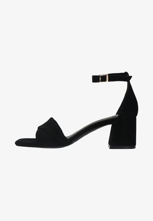 Sandale à talons en suède noir avec un bout carré, une bride ajustable à la cheville et un talon bloc. Design minimaliste avec une texture lisse.